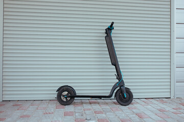 the electric scooter stands near the garage. ecology and movement concept
