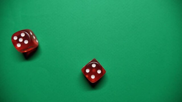 Red dice falling on green table. The Numbers 5 and 4 Appear on the Dice.