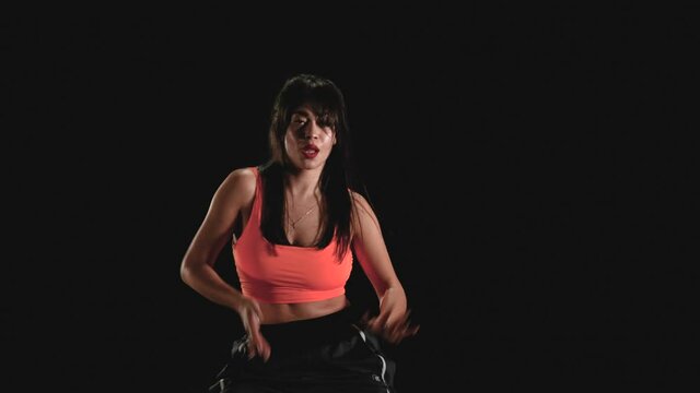 Young woman dancing hip hop on a black background. Slow motion