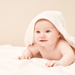 Cute small boy lying at bed. Childhood bath concept. Light background. Smiling child. Happy emotion. Copyspace. Stay home. Towel mockup