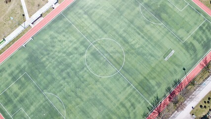 Aerial view of soccer football field. Mini goal post can be seen. People are walking on the jogging track.