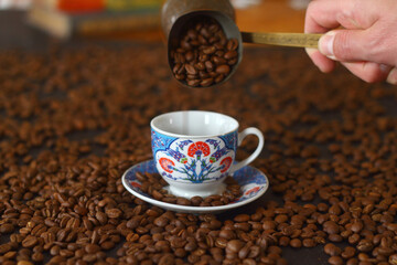 Male hand pouring Turkish coffee. cup of coffee with beans