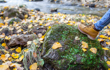 Child boy leather boot over mountain stream rock