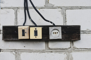 Old rustuc electrical outlet on white brick wall.