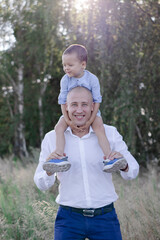 Obraz premium Bald dad and little son in the field or forest on sunny summer day. father's day.