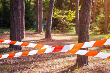 Red and white barrier tape, fenced off dangerous place or crime scene in the forest