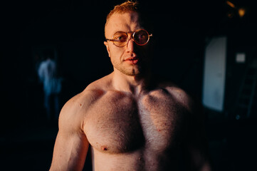 Muscular fitness shirtless man in glasses.
