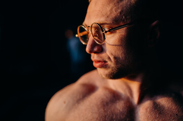 Muscular fitness shirtless man in glasses.