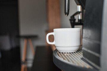 Detail of a coffee maker machine with a cup of coffee. Selective focus. 