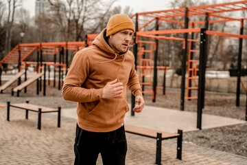 Fototapeta na wymiar Young man in sports outfit doing morning workout outdoors. Young man running on street sports ground. Staying fit and healthy concept