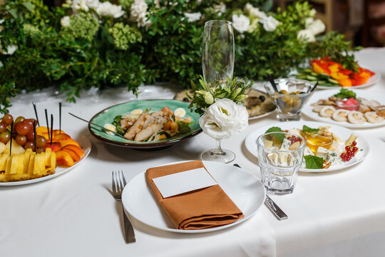 Wedding table setting with blank guest card, napkin, succulent and dish on a wooden plate. Rustic decor in brown tones