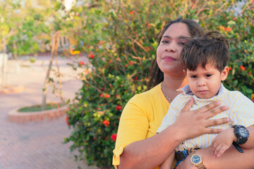 Obraz premium Young woman holding her child in her hands in the park