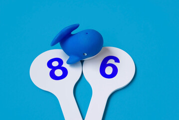 World Ocean Day June 8. A whale toy and figures isolated on a blue background like the ocean.
