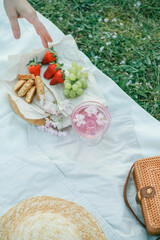 Spring picnic in nature. A glass of pink champagne with sakura flowers, a wicker bag, a hat, Italian. Wine. Spring.