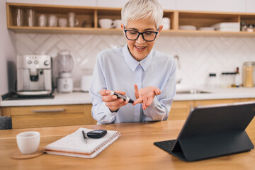 Senior woman checking blood sugar level at home.