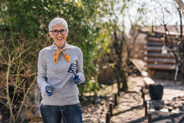 Portrait of a smiling senior woman doing spring cleaning and gardening at her backyard.