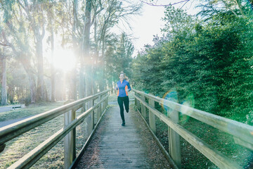 Young elite athlete woman training sprints on a wooden walkway at sunset in spring or summer hard training concept. concept daily training personal care