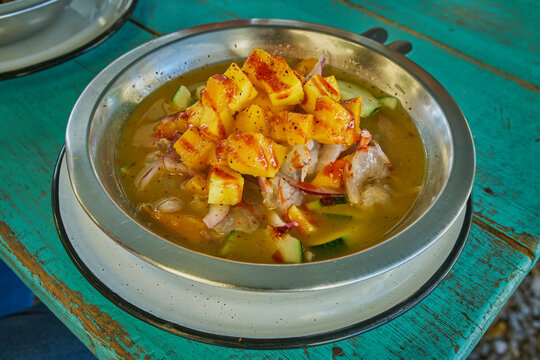 Camarones en aguachile servidos en plato de metal sobre un fondo azul verdoso