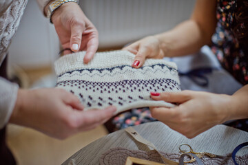 Two Women Holding a Hand-Knitted Woolen Wristband with Nordic Pattern