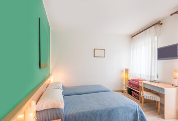 Beautiful and modern home and hotel bedroom interior design. Green walls, blue blankets and hardwood floor.