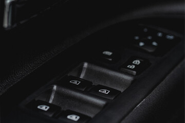 Obraz premium Close up view of button controlling window in modern car interior. Vehicle interior detail. Door handle with windows controls