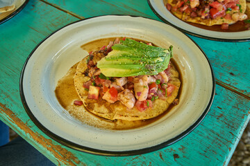 Camarones en aguachile servidos en plato de metal sobre un fondo azul verdoso