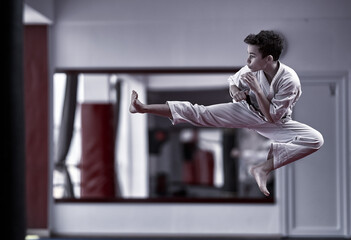 Young karate fighter doing a jump kick
