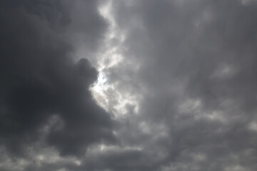 Dramatic gray sky in cloudy weather with glimpses of light. Meeting, collision of clouds. Angry stormy heaven.