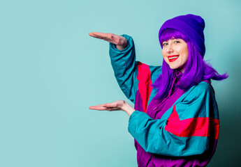Smiling white girl with purple hair and 80s tracksuit on blue background