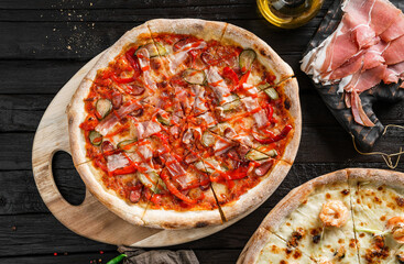 Pizza Pepperoni with prosciutto, sausage, cucumbers, cheese, tomatoes on dark wooden background. Fast food lunch for picnic company, top view