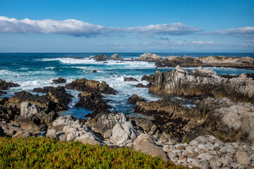 Fototapeta na wymiar Waves break along the rocky coastal shores of the Monterey Bay at Asilomar Beach, in Pacific Grove, along the central coast of California.