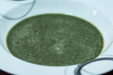 Nettle cream green soup in white plate