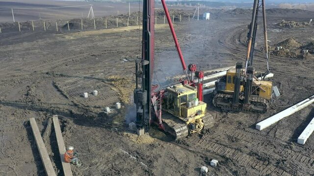 Excavation at a construction site, diesel pile driving machine with rumble and smoke drives piles deep into the ground to ensure the strength of the foundation of the future structure
