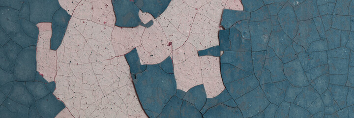 Peeling paint on the wall. Panorama of a concrete wall with old cracked flaking paint. Weathered rough painted surface with patterns of cracks and peeling. Wide panoramic texture for grunge background