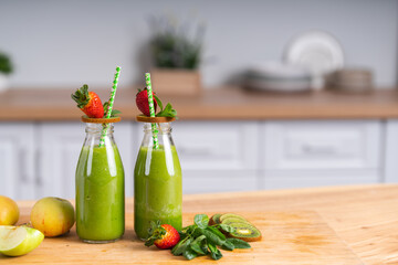 Close-up of two green fresh smoothie bottles with ingredients.