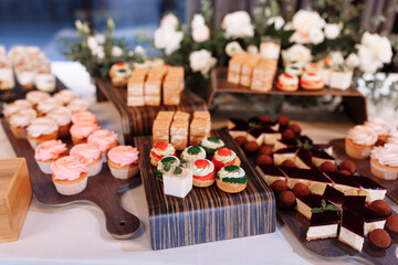 candy bar decorated by delicious sweet buffet with cupcakes, eclairs, sweetness and flowers, and other desserts, candy, Dessert table for a wedding or birthday party.