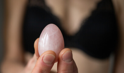 woman holding in hand a vaginal (yoni) egg. Rose quartz crystal jade egg.
