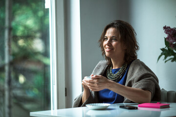 Fototapeta premium Woman drink tea sitting near the window of house.