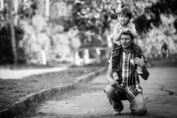 Portrait of daddy and his little son in the park. Black and white photo.