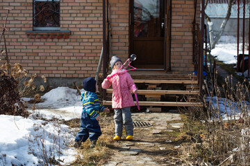 A girl and boy stand at the porch of house and play with soap bubbles