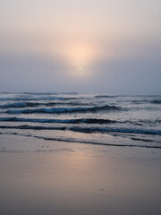 Sun setting into the Pacific Ocean in dense fog on the North Jetty beach - Ocean Shores, WA, USA