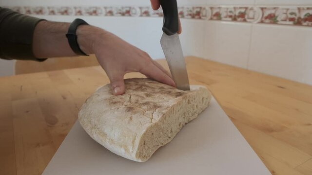 Close-up on hands cutting traditional bolo do caco bread of Madeira. Handheld shot