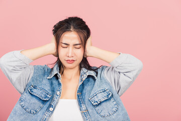 Asian portrait beautiful cute young woman wear denim have closed ears with hand palms and close eyes, studio shot isolated on pink background, Thai female covers ears for loud noise with copy space