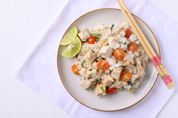 Fried rice with tofu, mung bean sprouts and tomato on dish with chopsticks on white background, Asian healthy vegan food