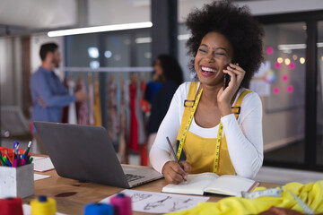 American woman fashion designer wearing tailor's tape measure talking by smartphone smiling