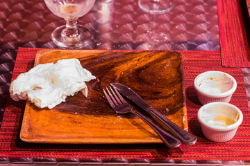 An empty plate left after a delicious meal. Cutlery, napkin and used dip containers can be seen amidst the aftermath