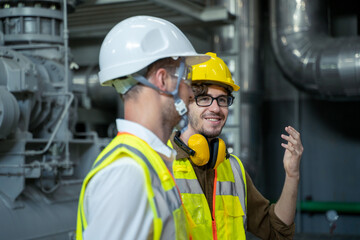 Industrial engineers discuss details with factory worker while using tablet computer working at heavy Industry Manufacturing Facility.