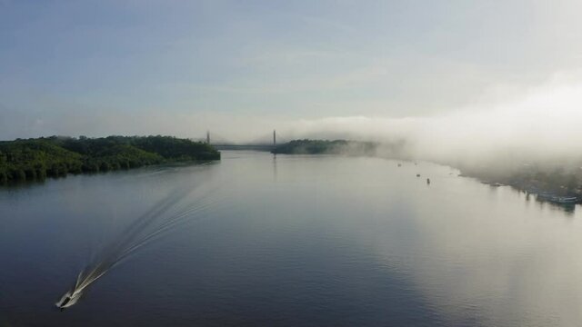 BINACIONAL DRONE AMAPA AMAZONIA DAWN WITH MIST BOAT ON THE OIAPOQUE RIVER DIVISES WITH FRENCH GUIANA