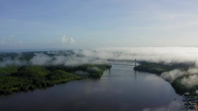 BINACIONAL DRONE AMAPA AMAZONIA DAWN WITH MIST BOAT ON THE OIAPOQUE RIVER DIVISES WITH FRENCH GUIANA