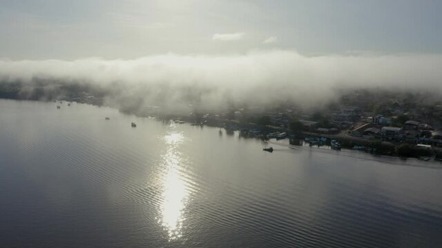 BINACIONAL DRONE AMAPA AMAZONIA DAWN WITH MIST BOAT ON THE OIAPOQUE RIVER DIVISES WITH FRENCH GUIANA
